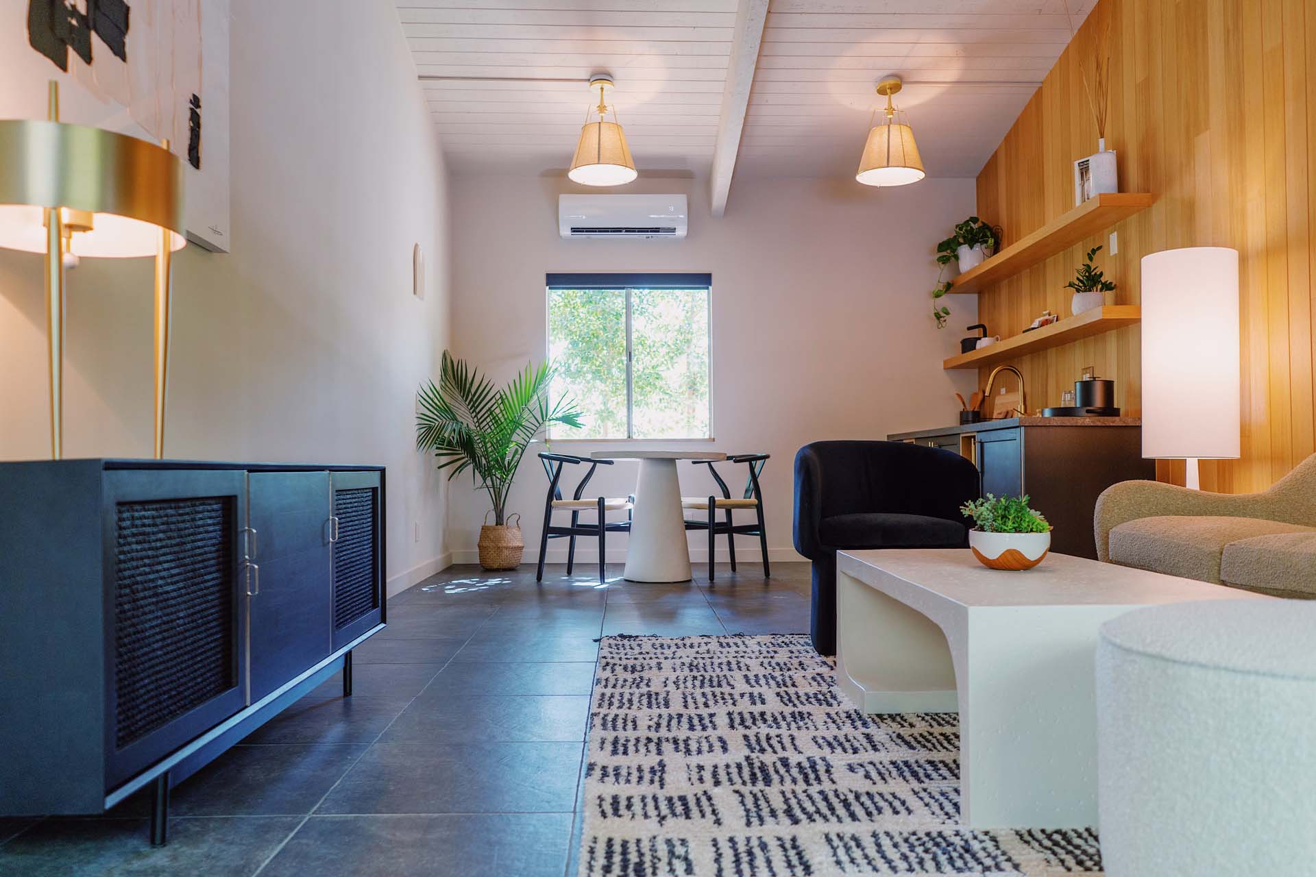 A wide view of a modern living room with a kitchenette, dining area, and seating area.