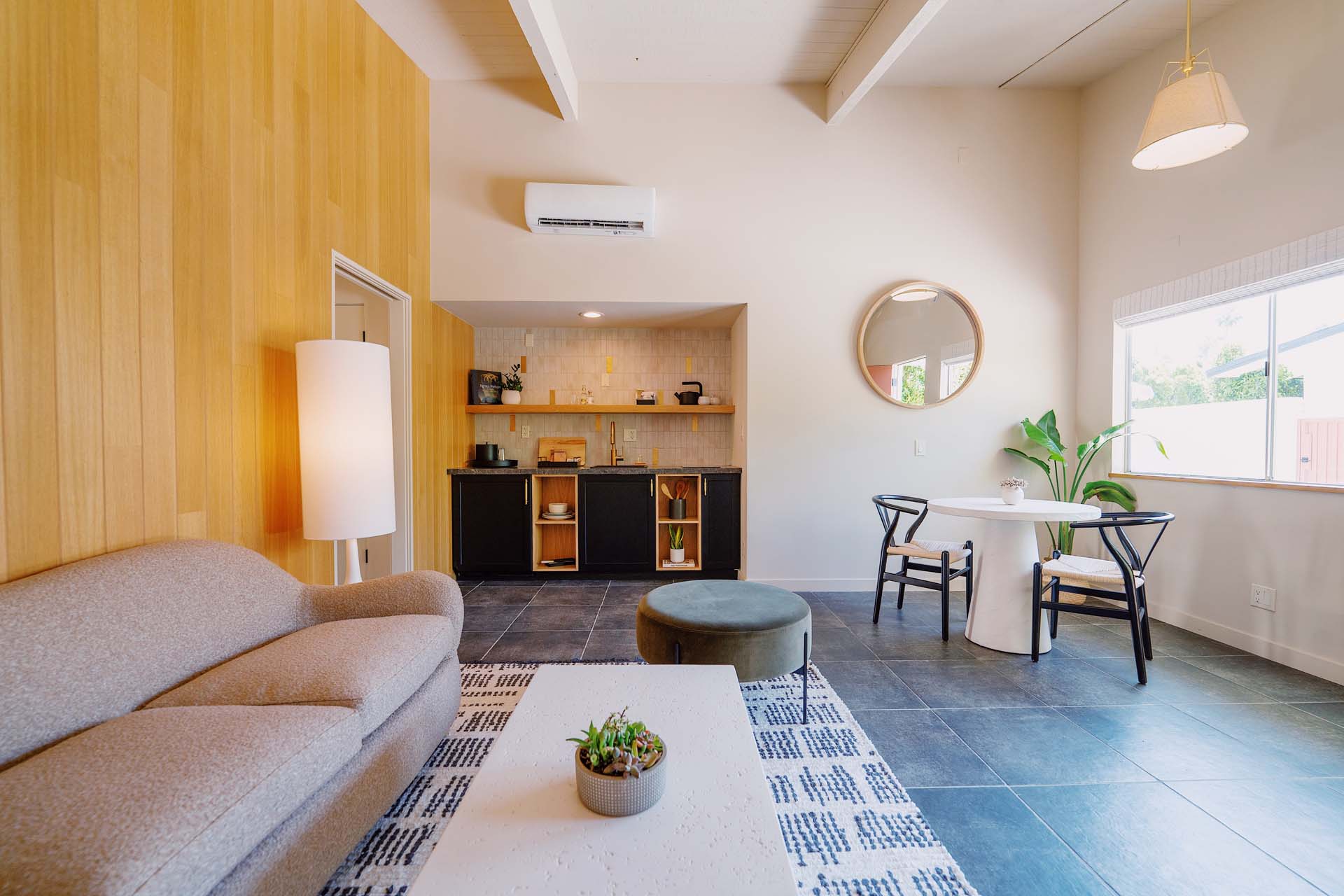 A wide view of a modern living room with a kitchenette, dining area, and seating space.