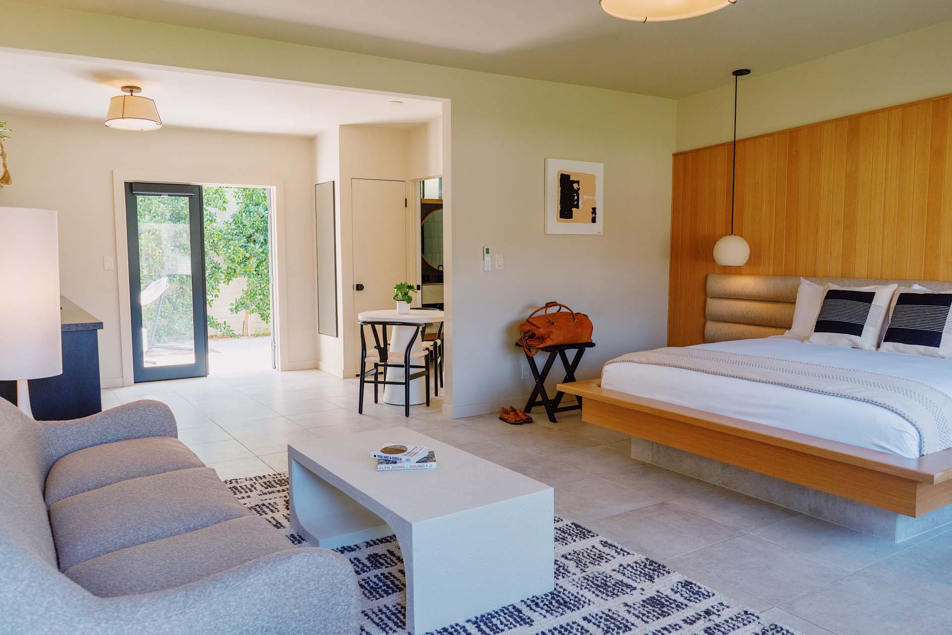 A wide view of a hotel room with a sofa, coffee table, bed, and doorway.