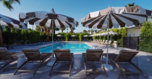 Golden evening light over Azure Sky Hotel mid-century pool courtyard in Palm Springs with adults relaxing