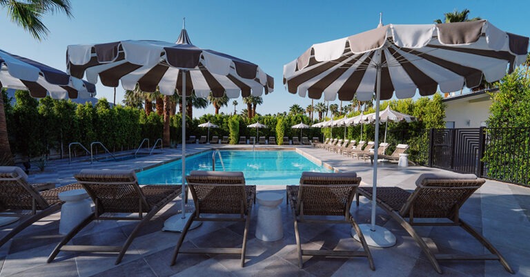 Golden evening light over Azure Sky Hotel mid-century pool courtyard in Palm Springs with adults relaxing