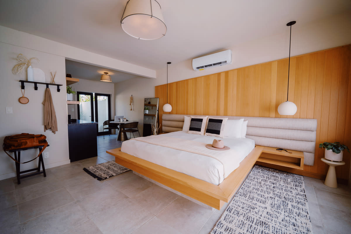 A wide view of a hotel room with a king-sized bed, wood paneling, and pendant lights.